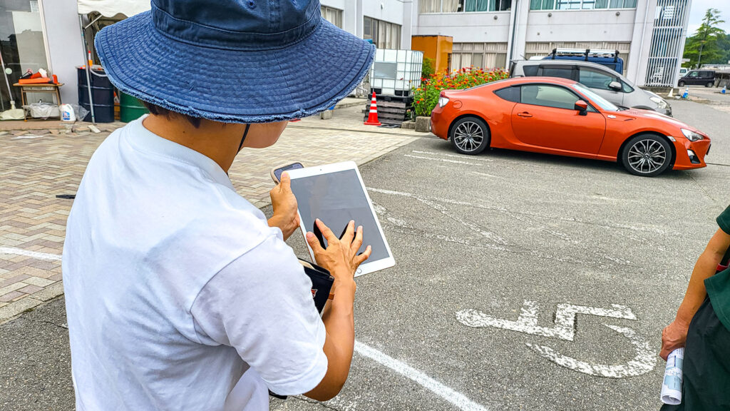 タブレットで以前の写真を見せるガイド 復興支援ツアー